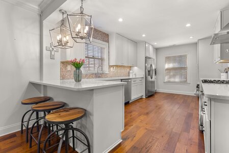 Stylish kitchen featuring white cabinets, pendant lighting, and natural light.