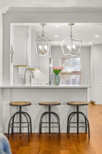Bright kitchen with white cabinetry, pendant lights, and a decorative vase of pink tulips.