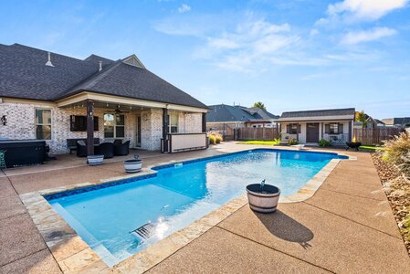 Stunning residential swimming pool surrounded by patio and cozy backyard setting.