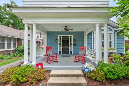 Porch with rocking chairs and inviting entrance to a stylish blue home.