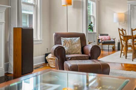 Comfortable leather armchair with decorative pillow in bright, stylish living space with natural sunlight.