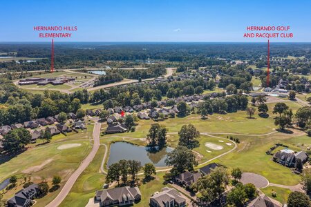 Alt text: Aerial view of Hernando Hills community showing homes, golf course, lake, tennis courts, and neighboring schools.