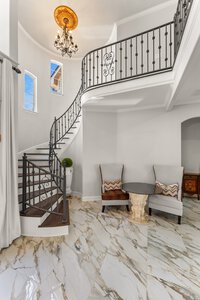 Luxurious interior featuring a sweeping staircase, marble flooring, and classic decor, showcasing upscale home design.