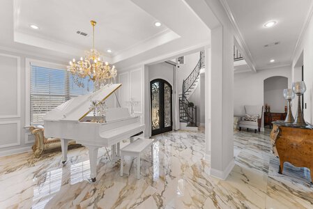 Elegant white grand piano with chandelier in sophisticated home interior, curated by John Langevin for luxury living.