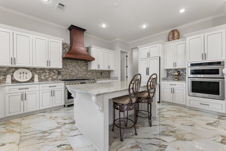Spacious kitchen featuring white cabinets, granite counters, and stainless steel appliances.
