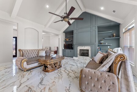 Luxurious living room with marble floors, custom-built cabinetry, and classic furniture, designed by John Langevin.