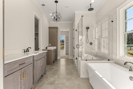 Elegant modern bathroom with large windows, dual vanities, walk-in shower, and soaking tub.