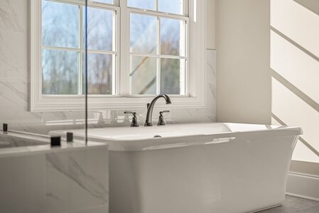Bright bathroom featuring a white bathtub and a large window for natural lighting.