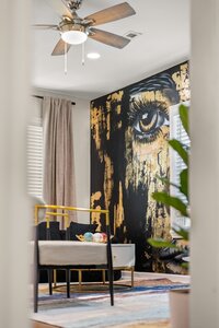 Vibrant art mural of a large eye in black and gold decorates the living room wall.