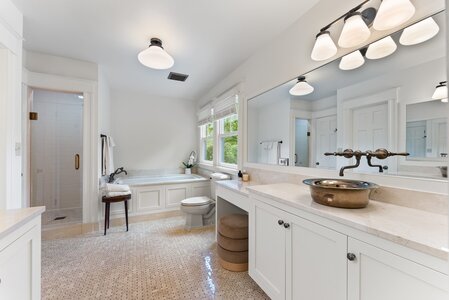 Spacious bright bathroom featuring a bathtub, vanity with unique sink, and natural light, perfect for relaxing.