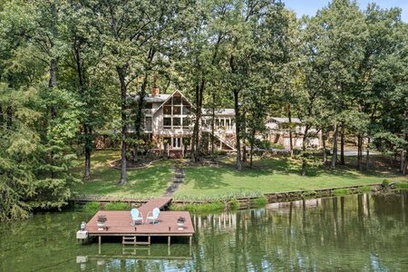 Stunning lakeside property featuring a private dock and vibrant greenery, perfect for outdoor relaxation.