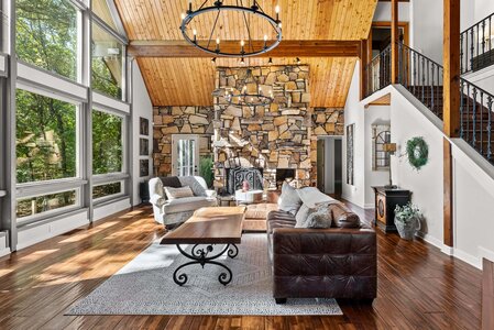 Bright, inviting living room with floor-to-ceiling windows, stone fireplace, and stylish decor highlighting luxury home design.