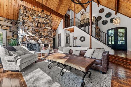 Spacious living room with stone fireplace and high wooden ceiling design.