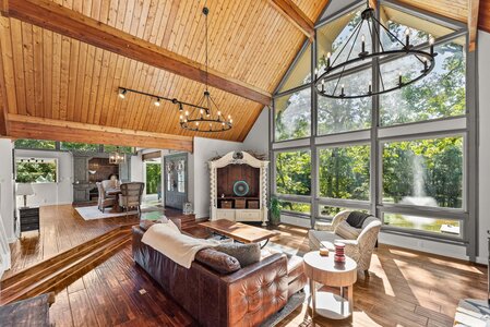 Bright interior with large windows and elegant chandeliers in a spacious living room.