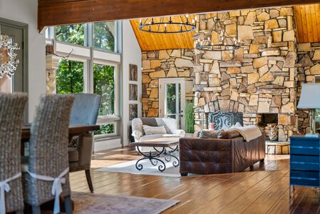 Stunning living room featuring a stone fireplace, large windows, and cozy seating with rustic decor.