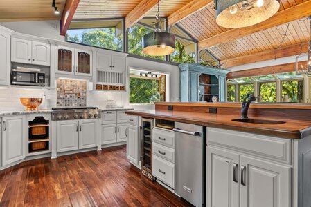 Bright kitchen featuring white cabinetry, wood accents, and expansive windows for a natural aesthetic.
