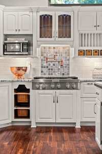 Bright kitchen with white cabinetry, stainless steel appliances, and copper accents.