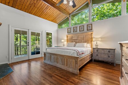 Bright master bedroom with natural light and wooden furniture.