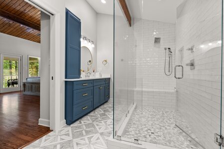 Bright bathroom with elegant blue vanity and walk-in glass shower. Stylish and functional design, perfect for luxury home renovations.