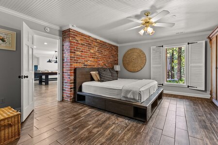Spacious bedroom featuring brick accent wall, large window, and stylish decor.