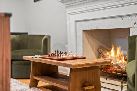 Warm fireplace with chess game and inviting seating area in living room.