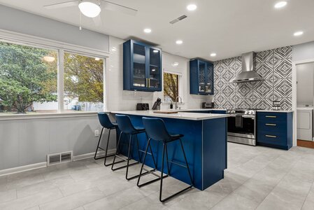 Elegant kitchen with blue cabinets, sleek stainless steel appliances, and stylish geometric backsplash.