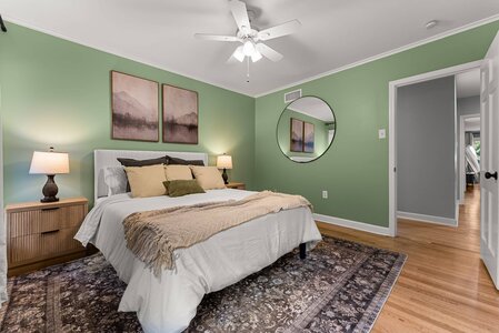 Bright and inviting bedroom featuring a green accent wall, modern decor, and comfortable bedding.