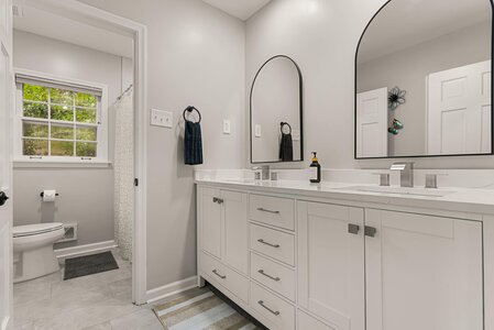 Clean and contemporary bathroom with dual vanities, sleek mirrors, and natural light.