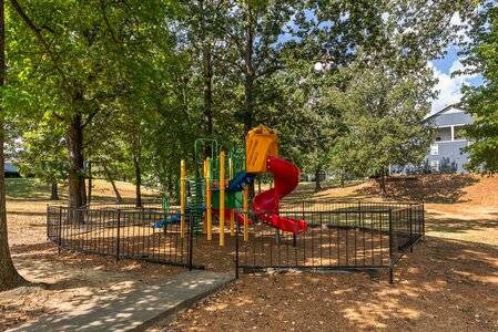 Colorful playground slide surrounded by fencing in a tranquil park setting.
