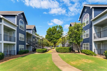 Stylish blue residential apartments with lush greenery and outdoor walkways.
