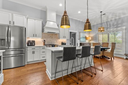 Bright, contemporary kitchen featuring white cabinetry, stainless steel appliances, and pendant lighting.