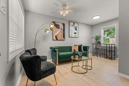 Stylish living room with green velvet sofa, black chairs, and contemporary decor.