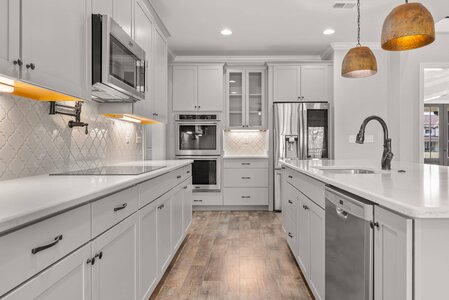 Bright, stylish kitchen featuring white cabinetry, stainless appliances, and elegant lighting.