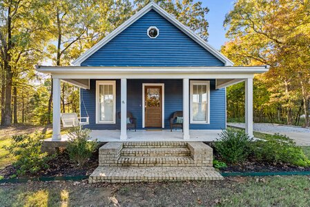 Bright blue house with welcoming front porch, surrounded by trees, perfect for home improvement projects.