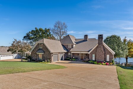 Luxurious brick house with a spacious driveway and lakeside views, perfect for upscale living and outdoor enjoyment.