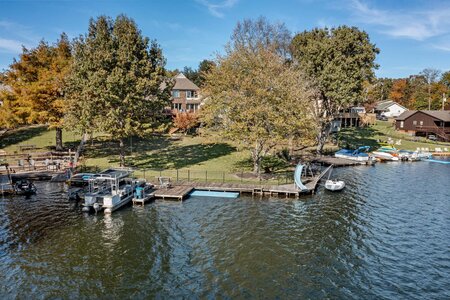 Beautiful lakeside home with boat docks and colorful autumn trees by the water.