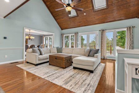 Bright living room with vaulted wood ceiling, large windows, and contemporary decor, ideal for family and social gatherings.