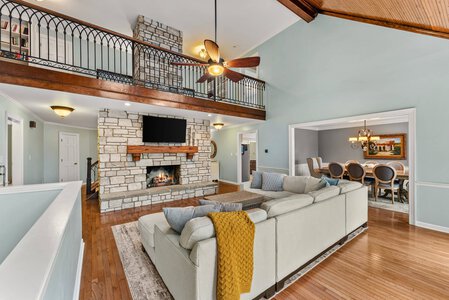 Spacious living room featuring stone fireplace, cozy seating, and high vaulted ceilings.
