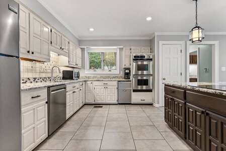 Spacious kitchen featuring stainless steel fridge, double oven, granite countertops, and ample cabinet storage.