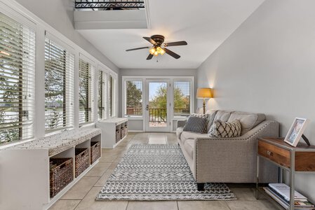 Bright sunroom with large windows, neutral decor, and stylish seating for relaxation.