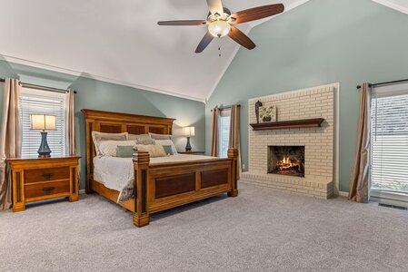 Comfortable master bedroom with cozy fireplace and classic wood furniture.