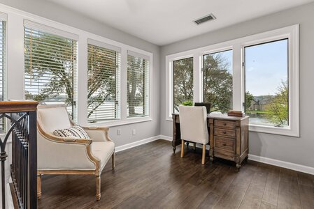 Bright home office overlooking scenic lake with large windows and hardwood floors.