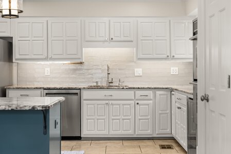 Bright white kitchen cabinets with granite countertops including modern appliances.