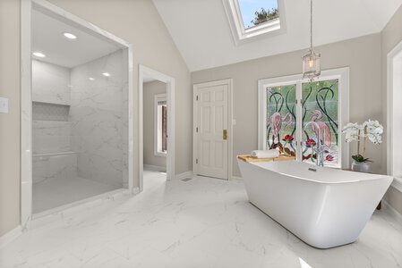 Spacious bathroom featuring a modern, minimalist design, walk-in shower, and elegant freestanding bathtub.