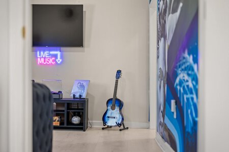 Neon "Live Music" sign and electric guitar in a modern music space for entertainment and relaxation.