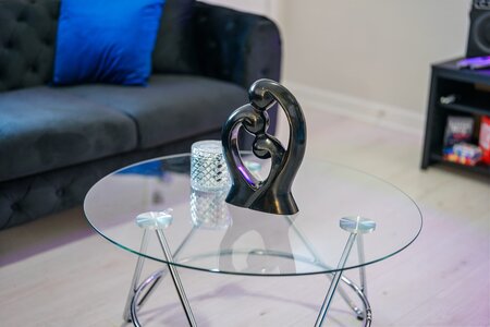 Elegant black sculpture of two lovers forming a heart on a glass coffee table in a contemporary living room.