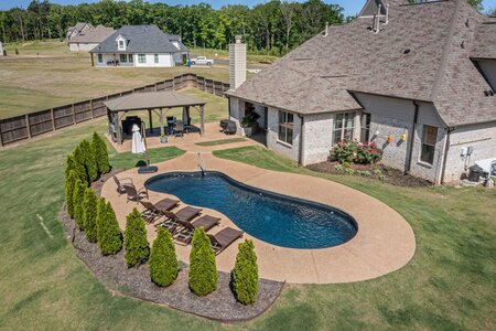 Beautiful backyard with pool, patio, and lush greenery for outdoor relaxation.