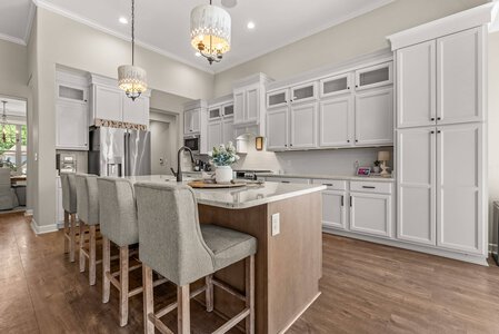 Elegant white kitchen with island, contemporary gray barstools, and stainless steel refrigerator, perfect for home improvement projects.