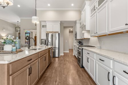 Bright spacious kitchen featuring white cabinetry, stainless steel appliances, and a center island with a natural wood base.