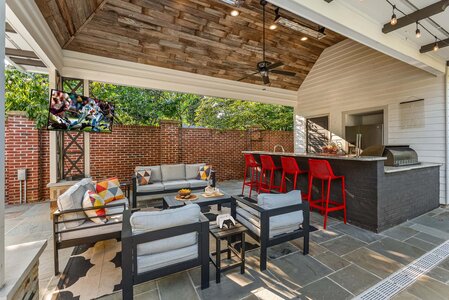 Modern outdoor lounge with bar, TV, and comfortable seating for entertaining.